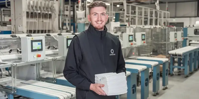 Johnsons Linen team member holding folded linen in their commercial laundry, an SEO and paid search client of Bigg.